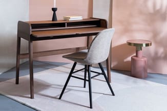 Houten bureau met zwarte rand en grijze stoel met zwarte poten, naast roze bijzettafel met gouden blad in minimalistisch inte