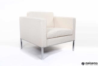 Crème gekleurde fauteuil met gestructureerde bekleding, armleuningen en metalen poten op witte achtergrond.
