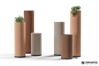 Collectie houten planters en zuilen in verschillende hoogtes, bruin en grijs gestreept, met planten erop. Meinema-logo rechto
