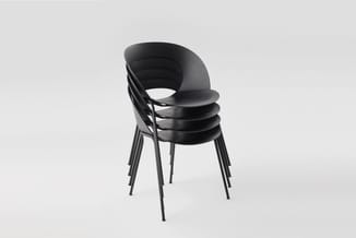 Zwarte kunststof stoelen met metalen poten gestapeld, moderne ergonomische vorm met geopend rugleuning-ontwerp.