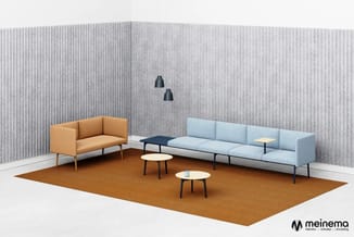 Ontvangstkamer met oranje twee-zitsbank links, lichtblauwe vier-zitsbank rechts, twee ronde tafels, bruin tapijt, grijze wand