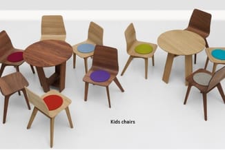 Kindersstoelen in verschillende houtsoorten en kleuren met gekleurde zitjes, gerangschikt rond twee ronde houten tafels.