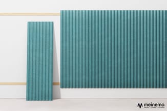 Twee turquoise geribde akoestische panelen tegen witte wand met houten rails, één staand en één horizontaal gemonteerd.