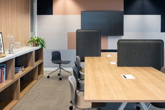 Modern kantoor met houten vergadertafel, grijze akoestische schermen, zwarte bureaustoel, houten kasten en kleurig geaccentue