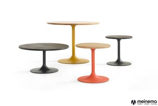 Vier pedestal tafels met rond blad: twee met zwart onderstel en donker blad, één met geel onderstel en licht blad, één met ro