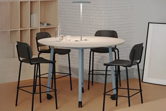 Ronde vergadertafel wit blad, grijsblauwe poten, met vier zwarte barstoeien op wieltjes in moderne kantoorruimte.