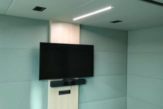 Moderne vergaderruimte met groene wandpanelen, witte houten muur met gemonteerde zwarte TV-scherm en soundbar, LED-verlichtin