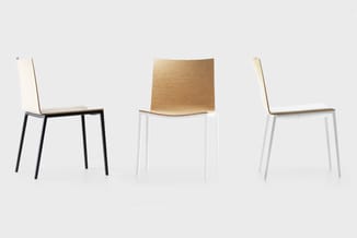 Drie moderne stoelen: links met wit zitting en zwart metalen onderstel, midden met natuurlijk houten zitting en wit onderstel