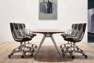 Moderne vergaderruimte met rond tafelblad, grijze bureaustoel met armleuningen en wielen, vier stuks rond tafel geplaatst.