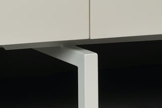 Hoekdetail van witte bovenkast en zwart bureau met grijs werkblad en witte afwerkingsstrip.