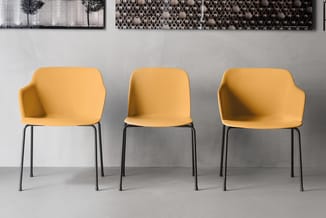 Drie gele stoelen met zwart metalen onderstel in moderne kantoorruimte met grijze wand en abstracte wanddecoraties.
