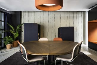 Vergaderruimte met donkergroene houten tafel, zwartblauwe stoelen met witte zitting, hangende koperen lamp, wit houten paneel
