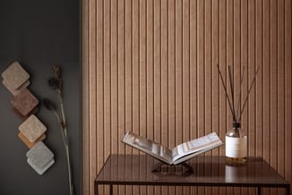 Minimalistische interieurinrichting met houten wandpanelen, donkere tafel met open boek, witte diffuser met stokjes, grijze t
