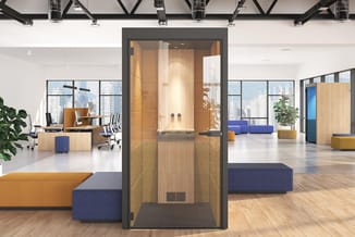 Modern kantoorinterieur met houten belcel centraal, blauwe en oranje modulaire zitbanken, houten bureaus met blauwe stoelen,
