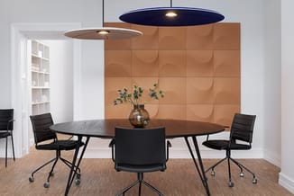 Moderne vergaderkamer met ronde zwarte tafel, vier zwarte stoelen met wielen, bruine 3D wandpanelen, houten vloer, twee hange