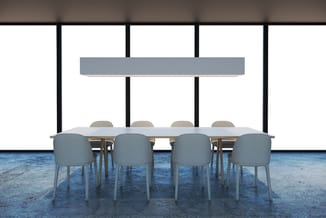 Moderne vergaderruimte met houten tafel, vier grijze stoelen en grijze wandpanelen tegen grote ramen.