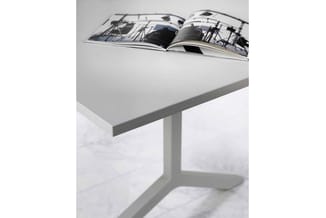 Witte kantoor- of salontafel met grijsblad en voetsteun, waarop een opengeslagen magazine met jachtbootafbeeldingen ligt.