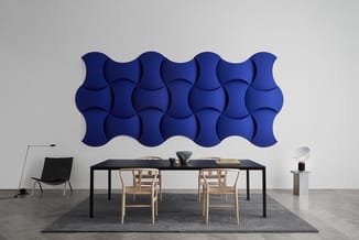 Modern kantoor met blauwe golfvormige wandpanelen, zwarte tafel, houten stoelen en grijze vloerkleed.