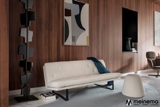 Moderne interieur met crèmekleurige bank op zwart metalen onderstel, houten wandbekleding, abstract kunstwerk, sculptuurachti
