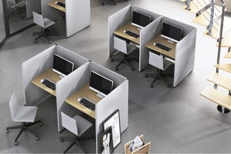 Kantoorruimte met witte akoestische werkboxen met houten bladen, computermonitoren, zwarte bureaustoelen en houten kasten op