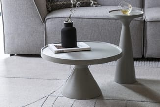 Witte conische bijzettafel met ronde blad in moderne minimalistische woonkamer, naast grijze bank en vloerkleed.