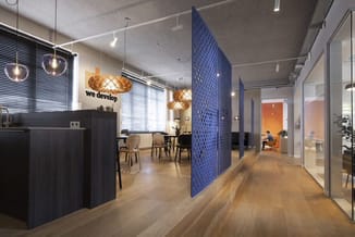 Modern kantoor met zwarte receptiebalie, blauwe akoestische scheidingswand, hangende gouden pendellampen en glazen kantoorrui