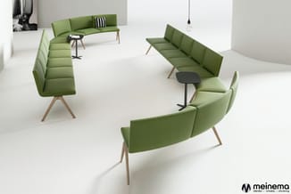Showroom met groene design zetels en banken met houten poten, zwarte tafeltjes, hanglamp en zwart-wit kunstwerk aan wand.