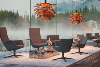 Moderne lounge met bruine en zwarte fauteuils, marmeren tafel, oranje hangende lampen en glazen wand met berglandschap.