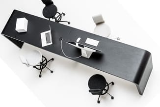 Bovenaanzicht zwarte bureau met witte laptops, zwarte en witte bureaustoel, zwarte microfoons en koptelefoons, witte tape.