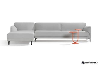 Grijze hoekbank met chaise longue links en twee rode bijzettafels, zwarte poten, op witte achtergrond. Meinema-logo rechtsond