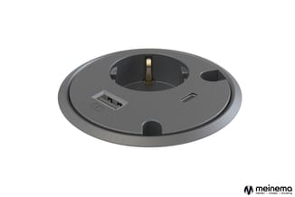 Grijs rond bureau-inbouw element met centraal stopcontact, USB-poort en kabelgat, bovenaanzicht.