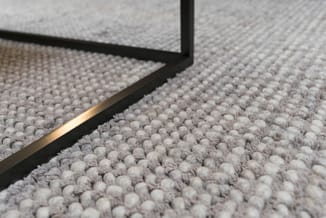 Grijze tapijttegel met zwart aluminium randenafwerking, bovenaanzicht detailopname textuur.