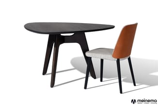 Zwarte ovale tafel met houten onderstel naast bruine stoel met lichtgrijs zitgedeelte en zwarte poten.