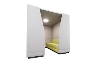 Akoestische belcel met witte stof beklede wanden, geel/groen zitbank, grijze plafond met ingebouwde verlichting.