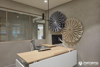 Modern kantoor met wit bureau met licht houten blad, grijze bureaustoel, glazen scheidingswand, zwart hangend accent, en twee