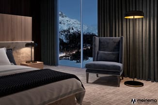 Luxe slaapkamer met grijs gestoffeerde fauteuil, houten bed, nachtkastje met lamp en grote raampartij met berglandschap uitzi