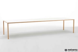 Lange rechthoekige vergadertafel met wit blad en houten frame in natuurlijke houtkleur, staande in heldere ruimte.