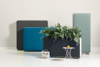 Mobiele akoestische schermen in grijs, blauw en groen met wieltjes. Zwart scherm met opgekweekte planten. Witte bijzettafel e