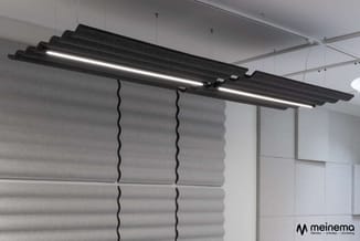 Hangende akoestische panelen in grijs met golvend patroon onder zwarte LED-pendellampen in moderne kantoorruimte.