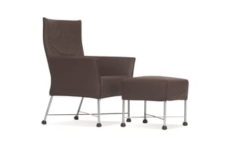 Bruine lederen fauteuil met voetenbankje op metalen poten met wieltjes, moderne vorm met hoge rugleuning.