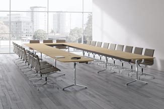 Moderne vergaderruimte met lange rechthoekige tafel in licht hout, zilveren poten, omgeven door grijze kantelstoelen met arml