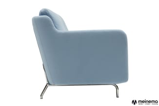 Lichtblauwe fauteuil met afgeronde vormen, gestoffeerd in zacht materiaal, op chromen poten tegen witte achtergrond.