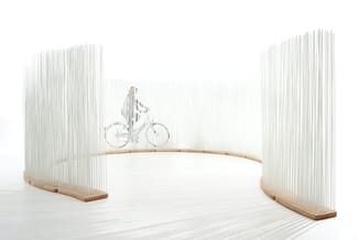 Curved acoustic panels in light wood with vertical white rods, showcasing a bicycle illustration in the center display area.