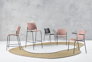 Moderne vergaderruimte met zes stoelen in roze en zwart rond een ovale witte rug op goudkleurig tapijt tegen betonnen muur.