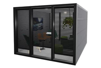 Zwarte akoestische belcel met horizontale latten en glazen panelen, zichtbaar interieur met plant en meubels.