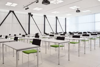 Moderne trainingszaal met witte tafels, zwarte stoelen met groene zittingen, zilveren frames en draagbare projectors aan het
