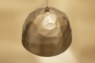 Hangende keramische pendant lamp in beige/crème met structureel oppervlak, gemonteerd aan metalen ophanging tegen beige wand.