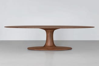Houten vergadertafel met ovaal blad en centrale voetsteun, donkerbruin gelakt, op neutraal grijze ondergrond.