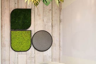 Moderne kantoorhoek met crèmekleurige loungestoel, groen tapijt, houten wand met moss wall art in groen en geel, hangende pla