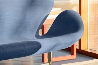 Grijsblauwe moderne fauteuil met organische, gebogen vormen en zwarte zitting, tegen raam in kantoor.